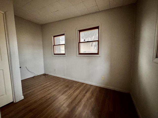 unfurnished room with baseboards and dark wood-style flooring