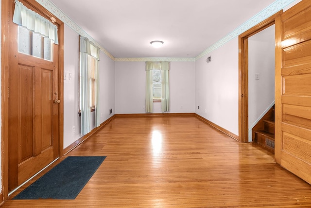 entrance foyer featuring light wood finished floors, baseboards, and crown molding