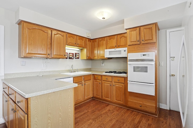 kitchen featuring a warming drawer, light countertops, a sink, wood finished floors, and white appliances