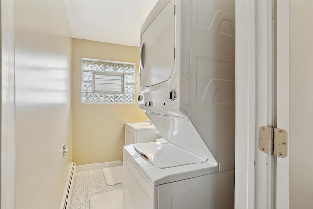 laundry area with laundry area, tile patterned floors, baseboard heating, and stacked washer and clothes dryer