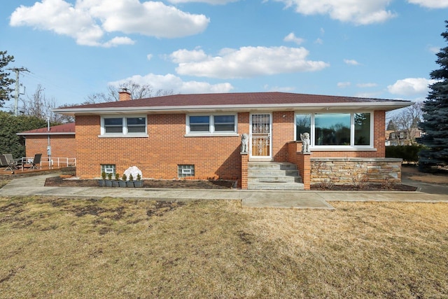 ranch-style house with brick siding, a chimney, and a front yard