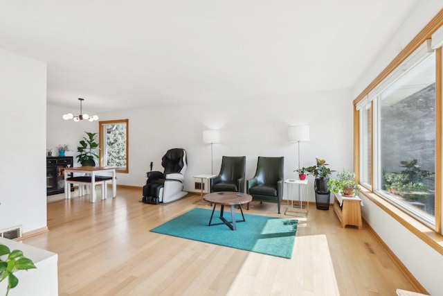 living area featuring a notable chandelier, visible vents, a wealth of natural light, and light wood-type flooring