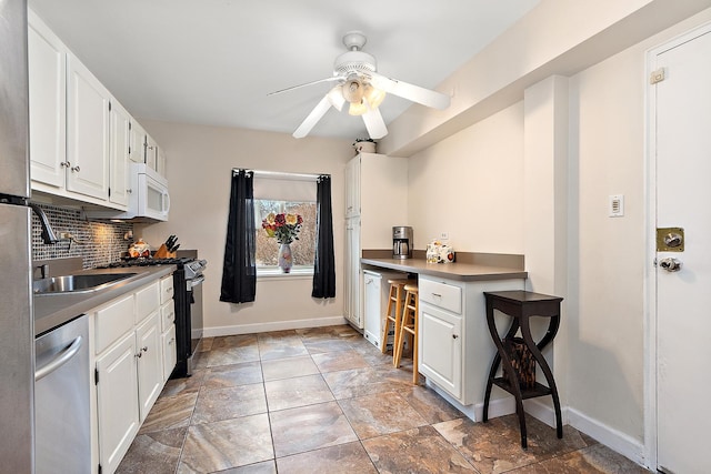 kitchen featuring a sink, white cabinetry, stainless steel dishwasher, backsplash, and black gas range oven