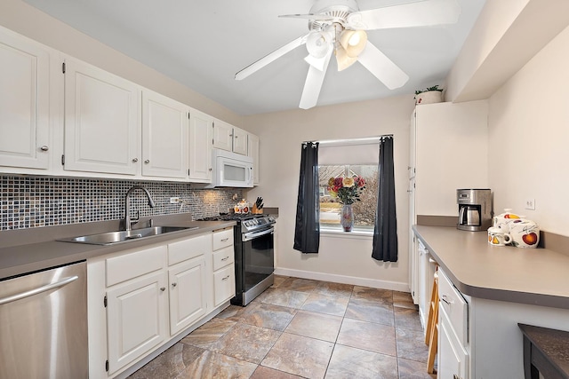 kitchen featuring appliances with stainless steel finishes, a sink, light countertops, white cabinetry, and backsplash