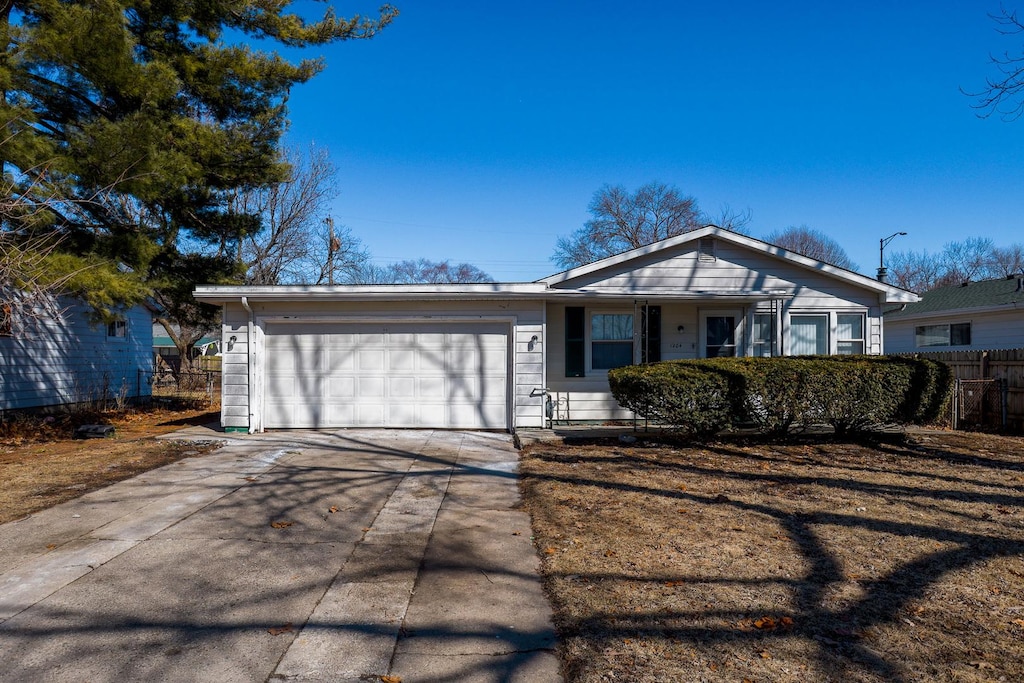 view of front facade featuring a garage, concrete driveway, and fence