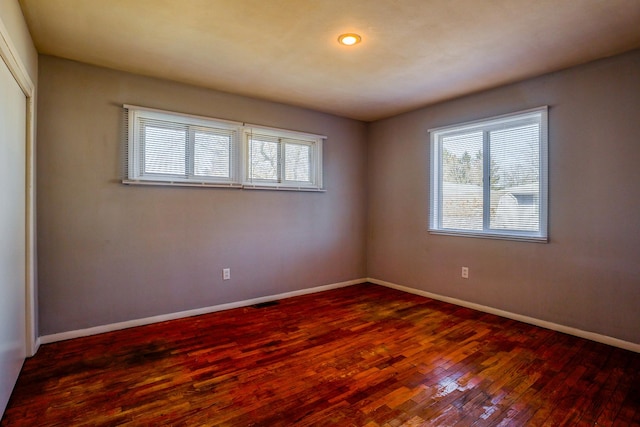 unfurnished room with dark wood-style floors, plenty of natural light, and baseboards