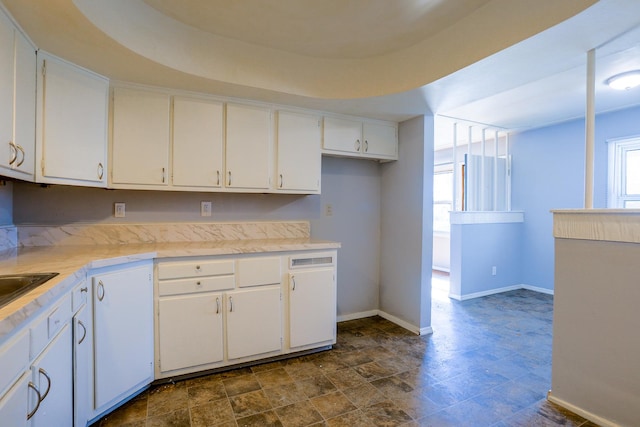 kitchen featuring light countertops, a healthy amount of sunlight, white cabinets, and baseboards