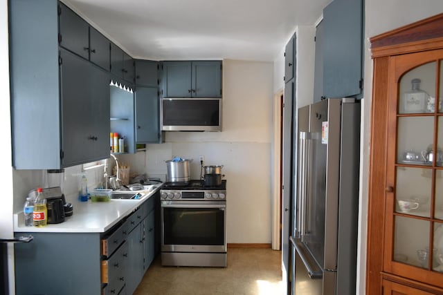 kitchen with stainless steel appliances, a sink, light countertops, blue cabinetry, and decorative backsplash