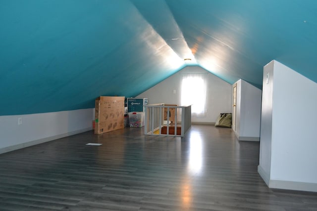 additional living space featuring baseboards, vaulted ceiling, and dark wood-style flooring