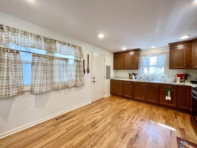kitchen featuring visible vents, baseboards, light countertops, light wood-style floors, and a sink