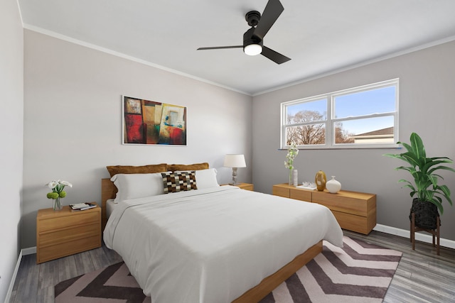 bedroom with a ceiling fan, crown molding, wood finished floors, and baseboards