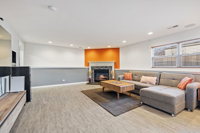 living area with light wood finished floors, visible vents, baseboards, recessed lighting, and a fireplace