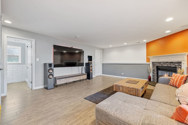 living room with a fireplace, recessed lighting, wood finished floors, and baseboards