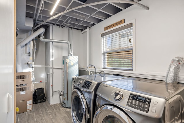 clothes washing area with gas water heater, wood tiled floor, laundry area, and washing machine and clothes dryer