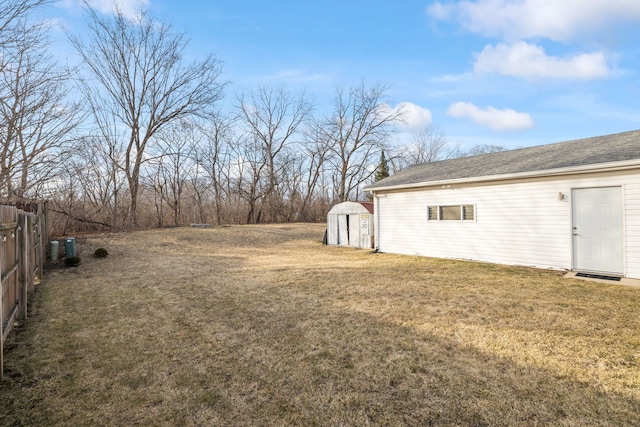 view of yard featuring an outdoor structure, fence, and a shed