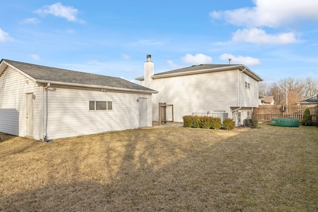 back of property featuring a lawn, a chimney, and fence