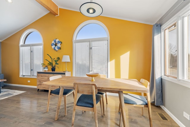 dining space with visible vents, wood finished floors, crown molding, baseboards, and vaulted ceiling with beams