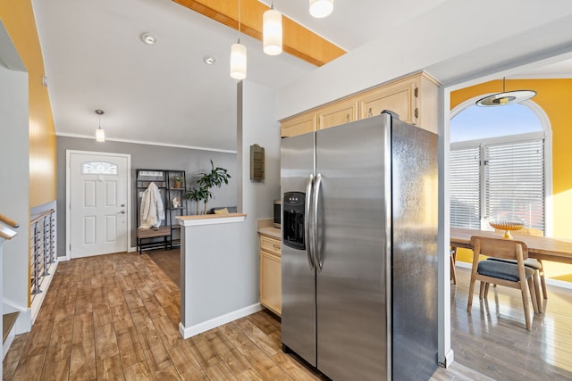 kitchen with light brown cabinetry, hanging light fixtures, light wood-type flooring, and stainless steel fridge with ice dispenser