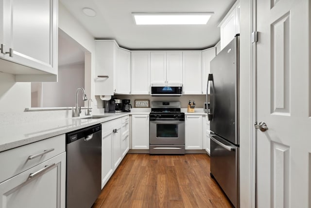 kitchen featuring appliances with stainless steel finishes, dark wood finished floors, white cabinets, and a sink