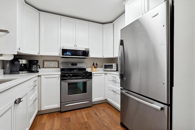 kitchen featuring light wood finished floors, light countertops, appliances with stainless steel finishes, and white cabinetry