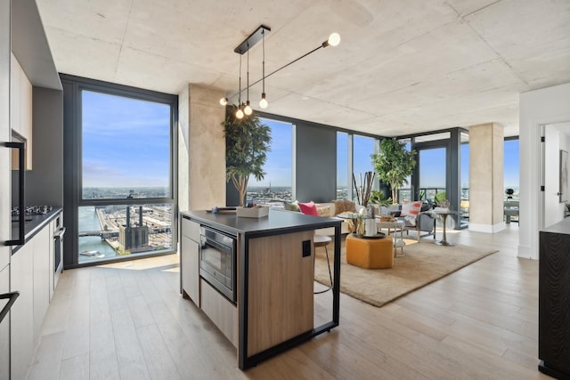 kitchen featuring a water view, expansive windows, dark countertops, modern cabinets, and decorative light fixtures