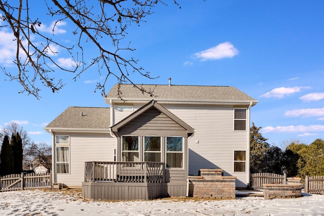 rear view of property with fence, a deck, and roof with shingles