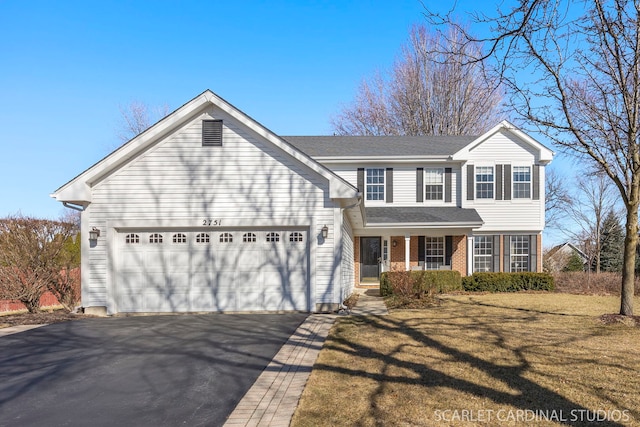 traditional home with brick siding, an attached garage, driveway, and a front lawn