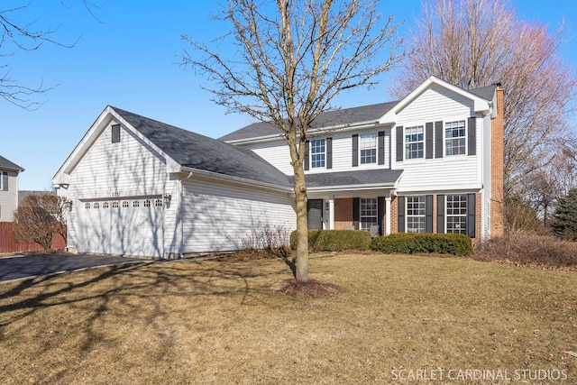 traditional home with a front yard, driveway, a chimney, a garage, and brick siding