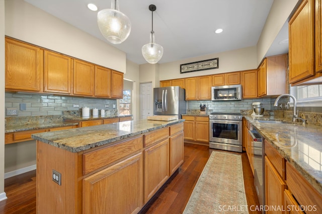 kitchen featuring a sink, a center island, appliances with stainless steel finishes, light stone countertops, and dark wood-style flooring