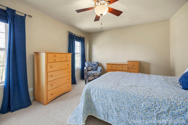 bedroom featuring light colored carpet, baseboards, and ceiling fan