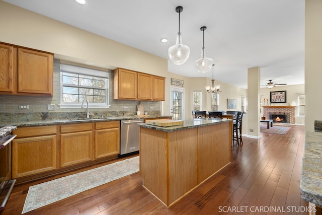 kitchen featuring a sink, a kitchen island, dark stone counters, and stainless steel dishwasher