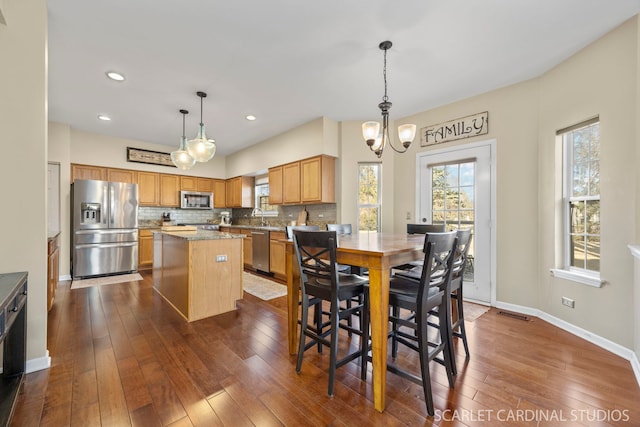 dining space featuring an inviting chandelier, plenty of natural light, dark wood-style floors, and baseboards