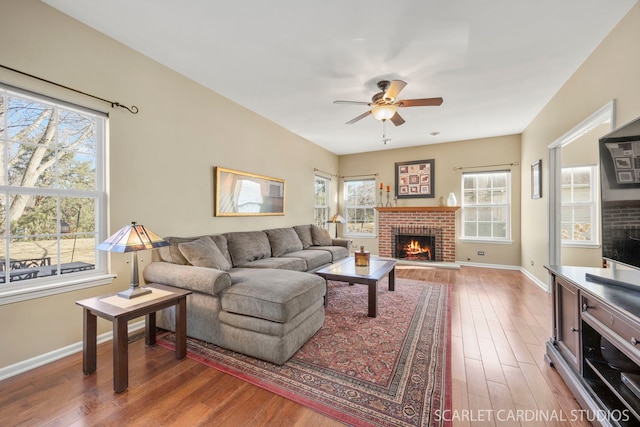 living area featuring a wealth of natural light, a fireplace, ceiling fan, and wood finished floors