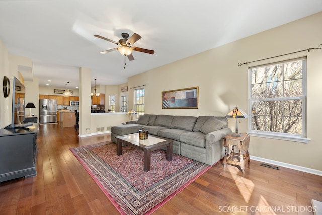 living area with visible vents, ceiling fan, dark wood-type flooring, and baseboards