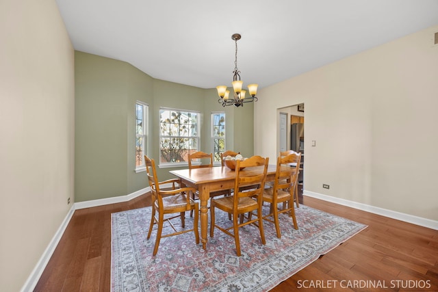 dining area featuring a chandelier, baseboards, visible vents, and wood finished floors