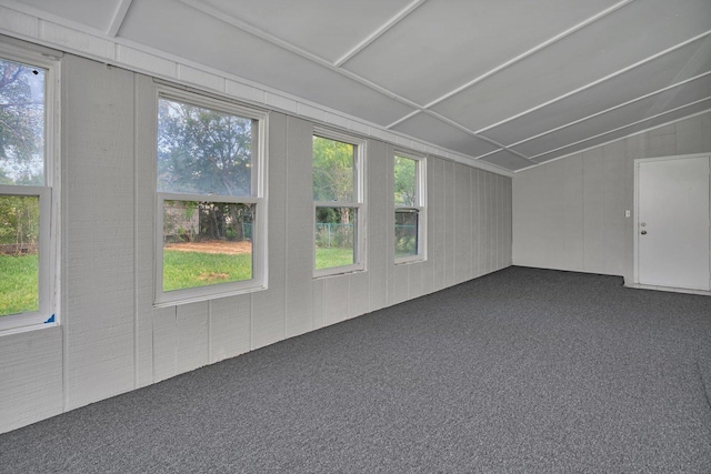 bonus room with dark carpet and vaulted ceiling