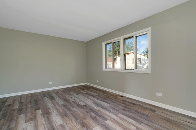 empty room with dark wood-style flooring and baseboards