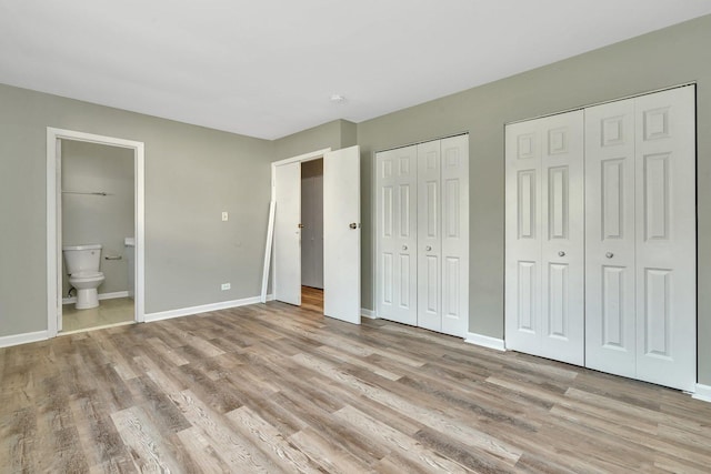 unfurnished bedroom featuring light wood-type flooring, two closets, and baseboards