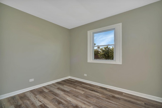 empty room with visible vents, baseboards, and wood finished floors