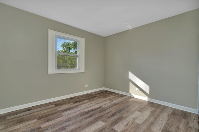 spare room featuring light wood-type flooring, visible vents, and baseboards