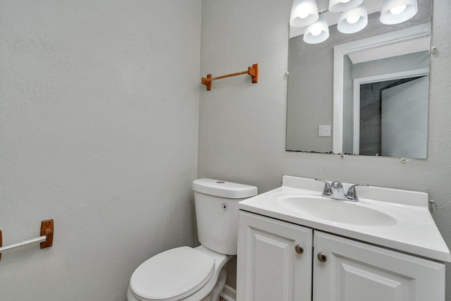 bathroom with a textured wall, vanity, and toilet