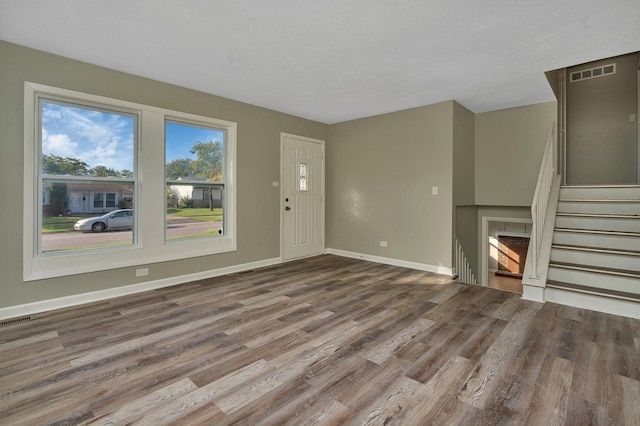 unfurnished living room with stairway, wood finished floors, visible vents, and baseboards