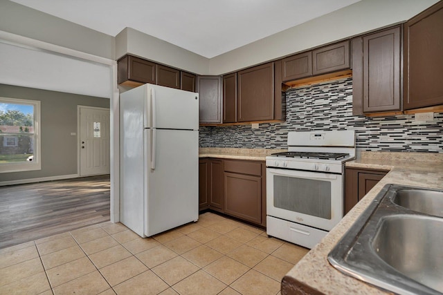 kitchen featuring light countertops, white appliances, light tile patterned flooring, and tasteful backsplash