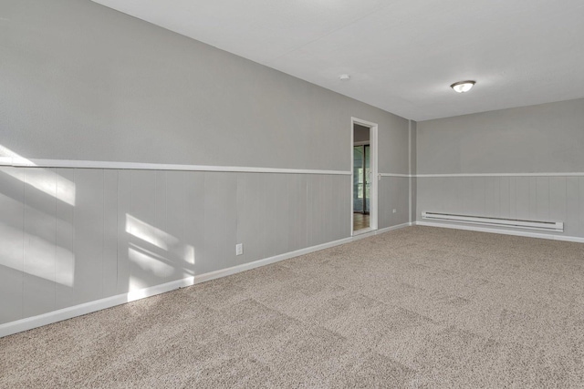 carpeted spare room featuring a wainscoted wall and baseboard heating