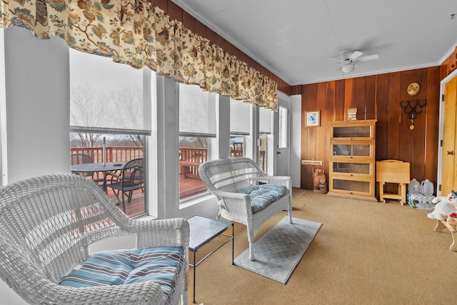 interior space with wooden walls, ornamental molding, and a ceiling fan