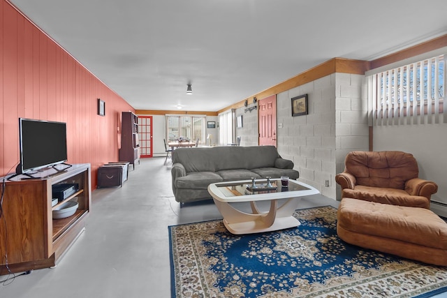 living area featuring a healthy amount of sunlight, concrete flooring, and concrete block wall