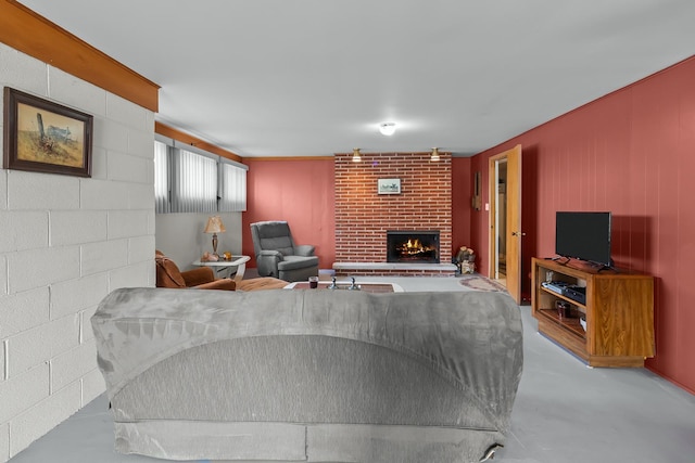 living room featuring finished concrete floors, concrete block wall, and a fireplace