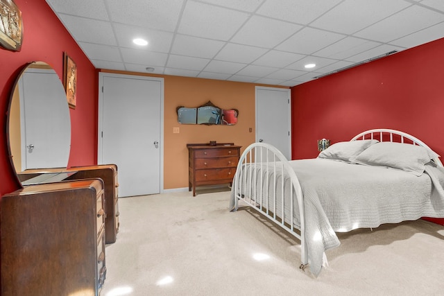 bedroom with a drop ceiling, recessed lighting, carpet floors, an accent wall, and baseboards