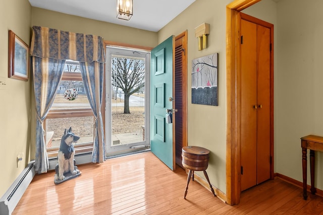 foyer featuring light wood-style flooring, a baseboard heating unit, and baseboards