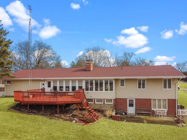 rear view of property with brick siding, a yard, a chimney, and a wooden deck